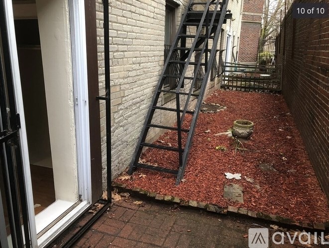 A red brick wall with a metal staircase outside a building.
