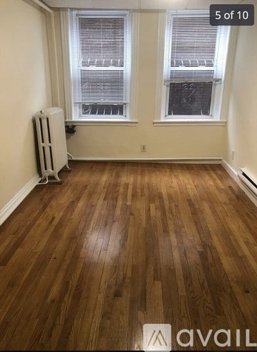 A room with wooden flooring and two windows.