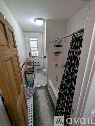 A bathroom with a shower curtain and a towel hanging on the door.