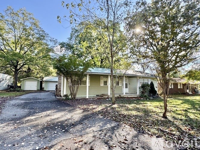 A house with a driveway and trees in front of it.