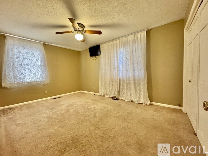A room with a ceiling fan and carpeted floor.