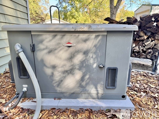 A gray outdoor wood stove with a hose attached to it.