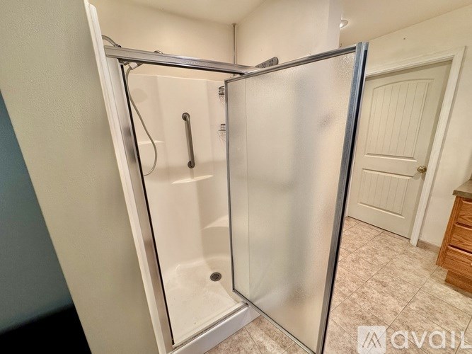 A stainless steel shower with a glass door is in a white bathroom.