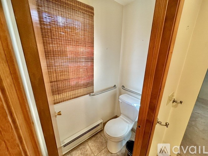 A bathroom with a toilet, sink, and window with blinds.