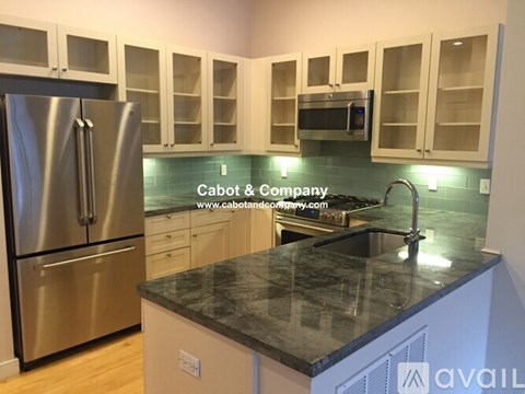 A kitchen with a stainless steel refrigerator and a granite countertop.