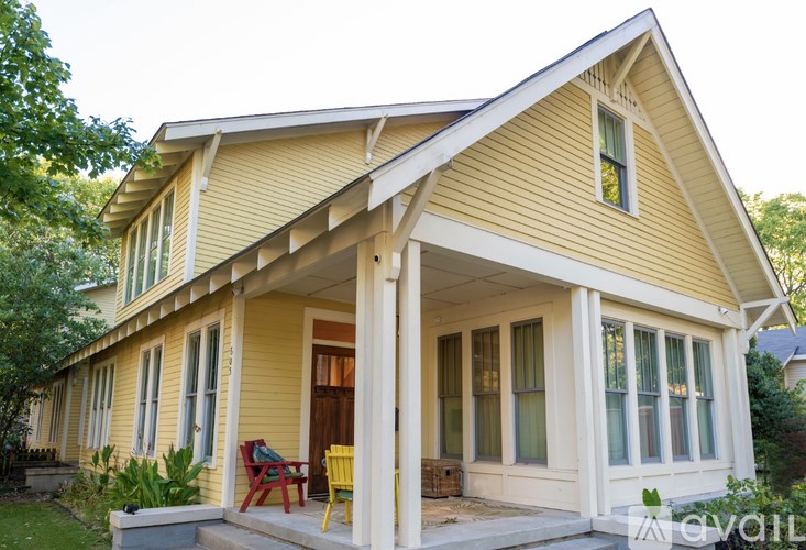 A yellow house with a porch and a red chair.