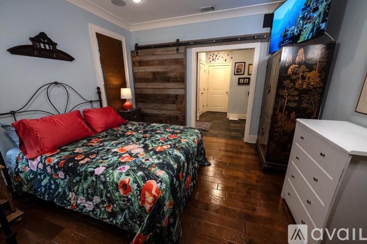 A bedroom with a bed, dresser, and a television.
