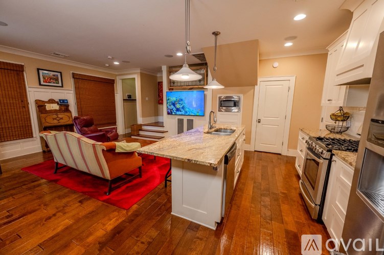 A kitchen with a red rug and a wooden floor.