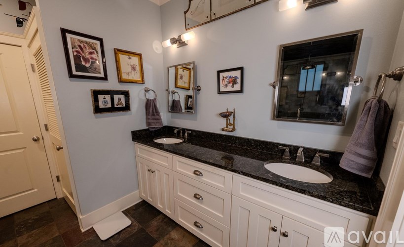 A bathroom with a black granite countertop and white cabinets.
