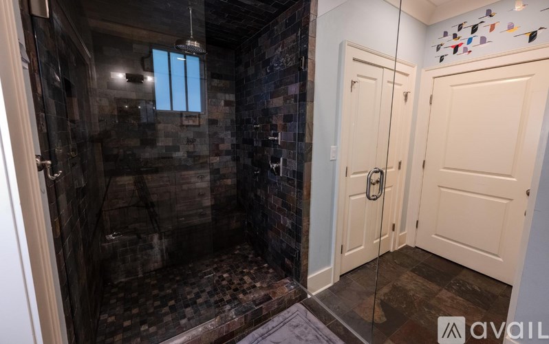 A bathroom with a walk-in shower and a white door.