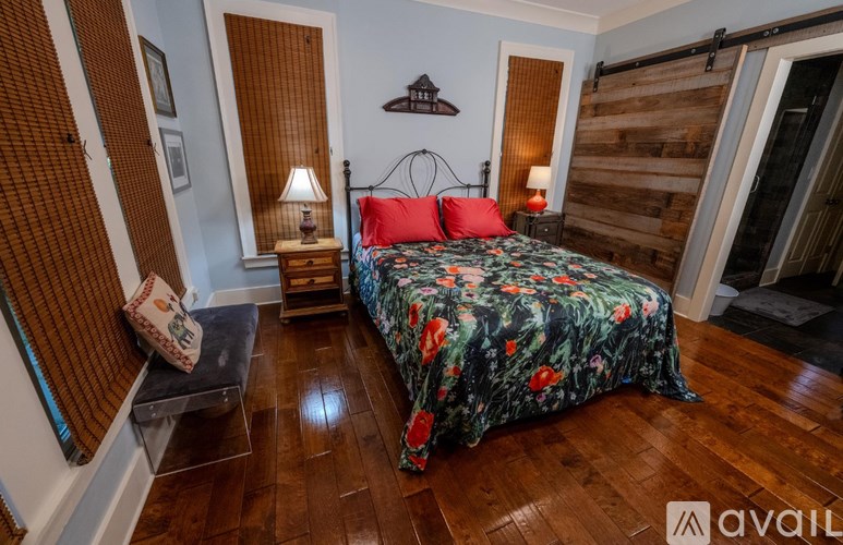 A bedroom with a floral bedspread and a wooden headboard.