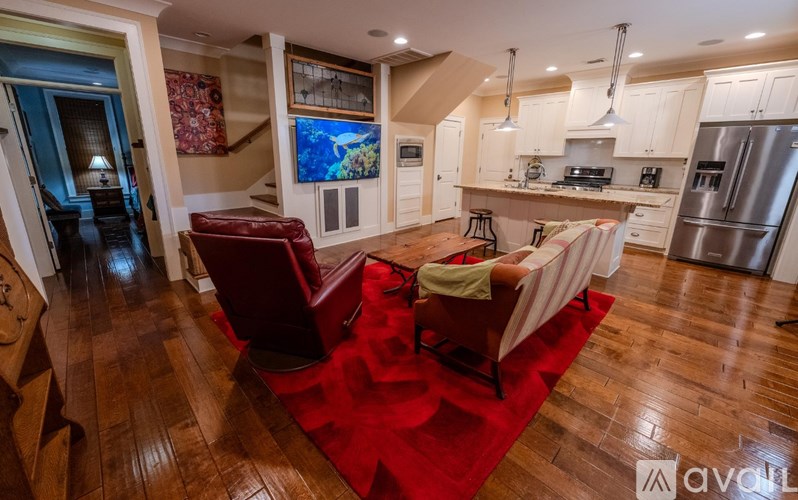 A living room with a red rug and a kitchen in the background.