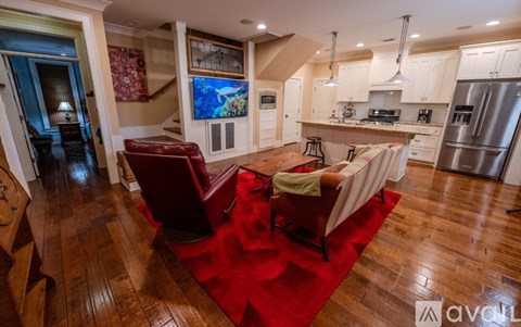 A living room with a red rug and a kitchen in the background.