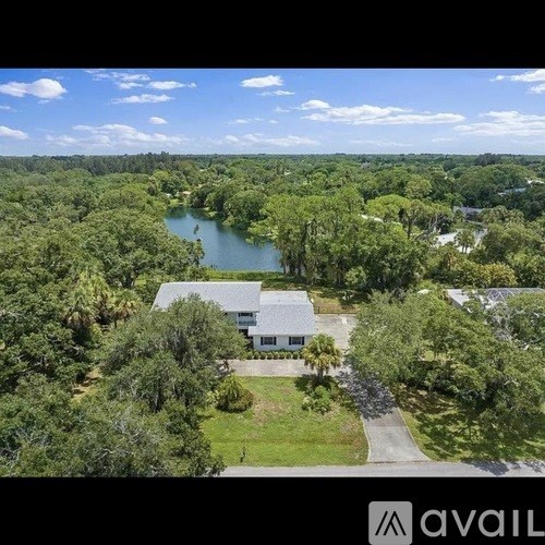 A house is surrounded by trees and a body of water.