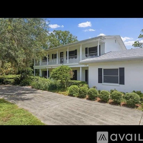 A white two-story house with a balcony and a driveway.