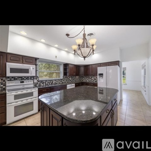 A kitchen with granite countertops and a chandelier.