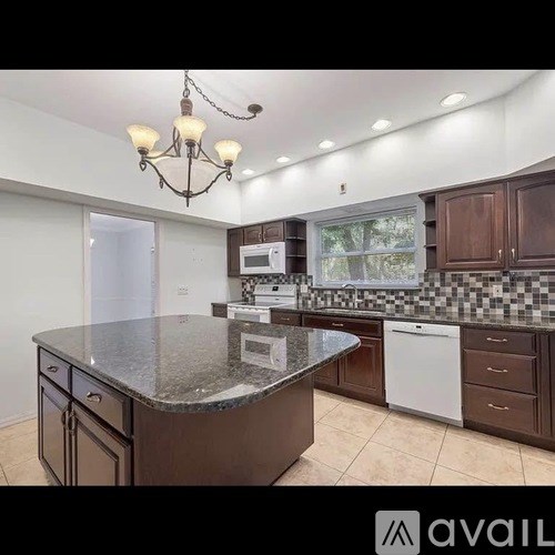 A kitchen with a granite countertop and a chandelier.