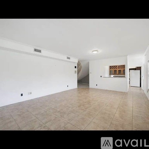 A spacious empty room with tiled flooring and white walls.