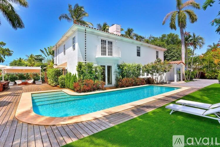 A white house with a pool in front.