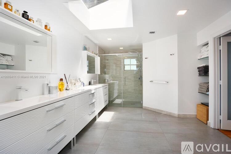 A modern bathroom with a skylight and a vanity with a mirror above it.