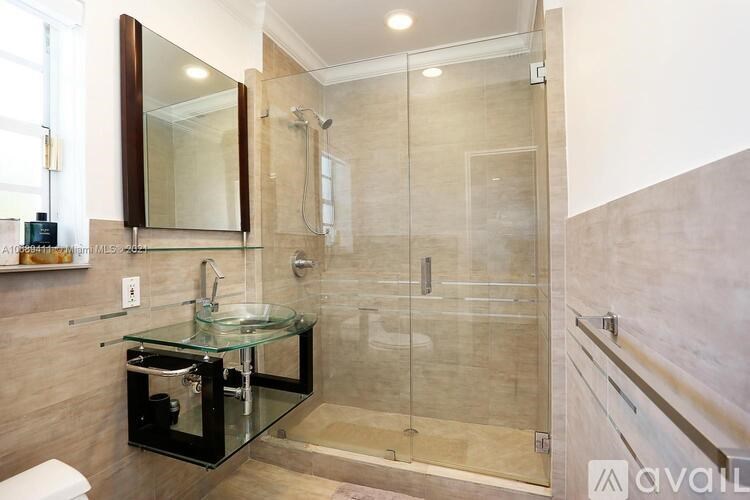 A modern bathroom with a glass table and walk-in shower.