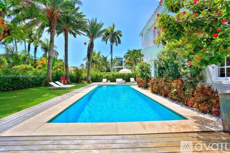 A pool surrounded by palm trees and red flowers.