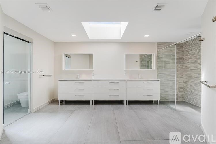 A modern bathroom with a skylight and a vanity with a mirror above it.