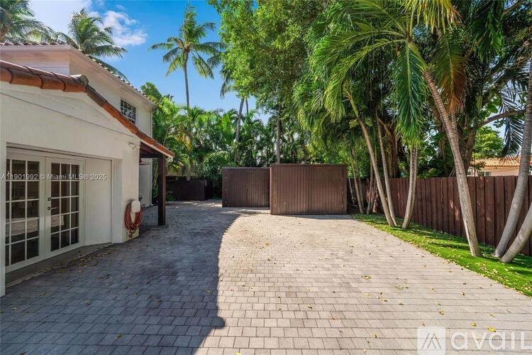 A house with a driveway and palm trees in the background.