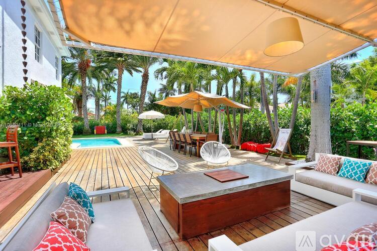 A sunny outdoor patio with a hot tub and lounge chairs.