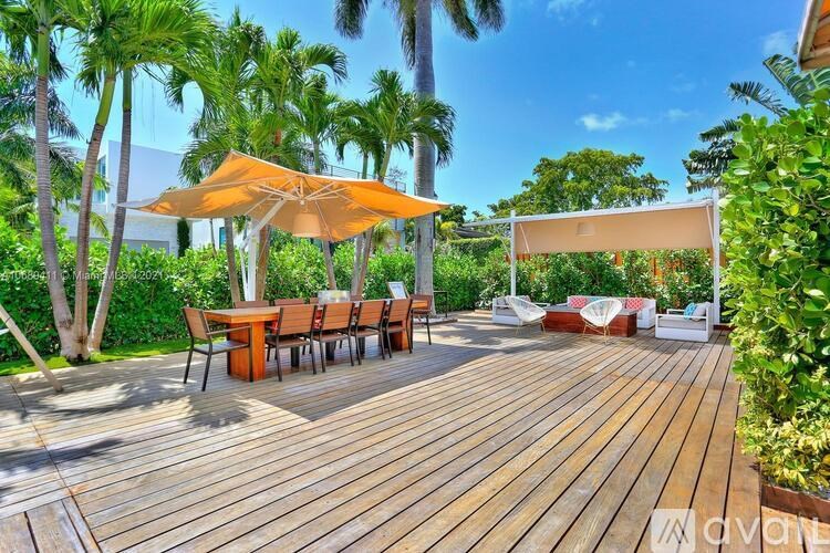 A wooden deck with a table and chairs under an umbrella.