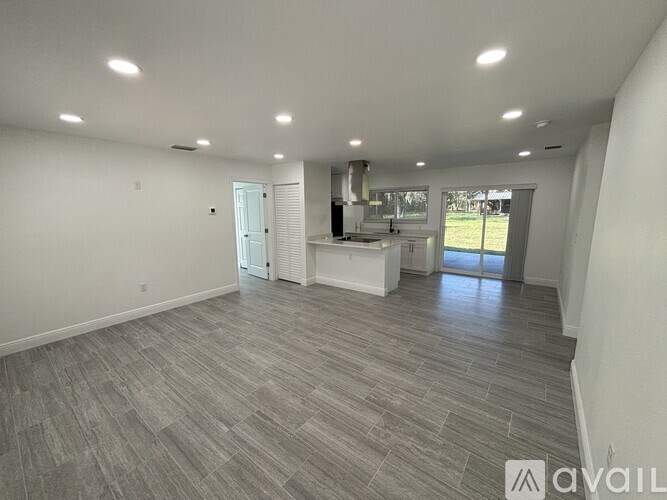 A spacious room with a kitchen area in the background.