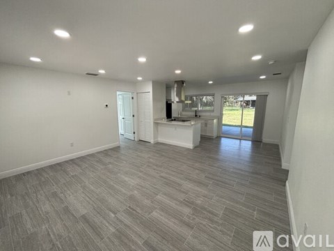 A spacious room with a kitchen area in the background.