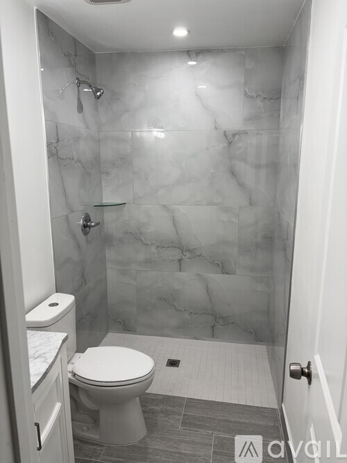 A white toilet sits in a marble bathroom.