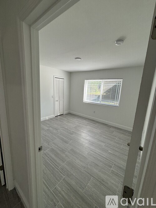 A room with a window and a door is available for rent.