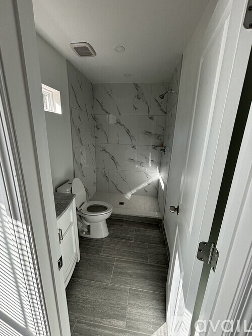 A bathroom with a toilet, sink, and marble wallpaper.