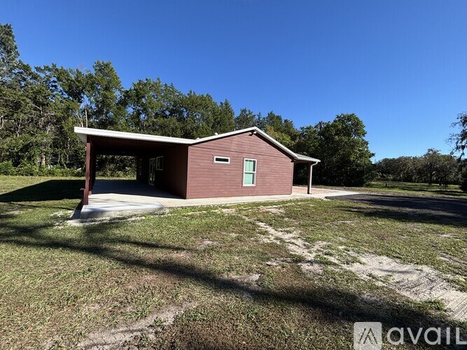 A small house with a red roof and a green window is surrounded by trees.