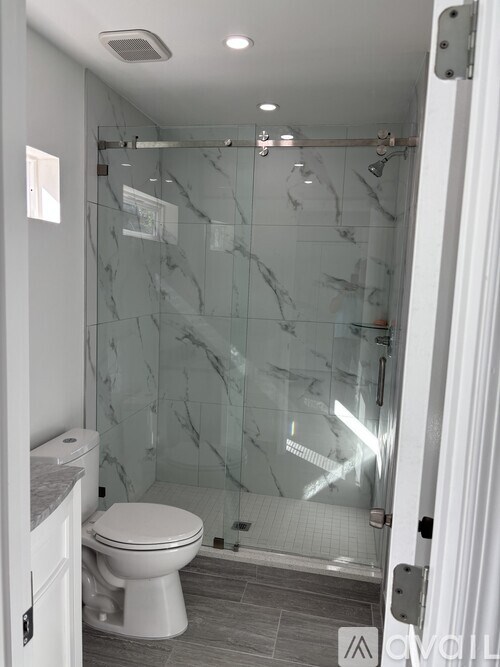 A white toilet sits in a bathroom with a glass shower stall.