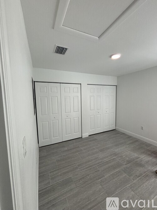 A room with two white doors and a grey floor.