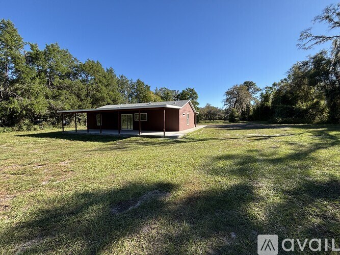 A small house with a porch is surrounded by trees and grass.