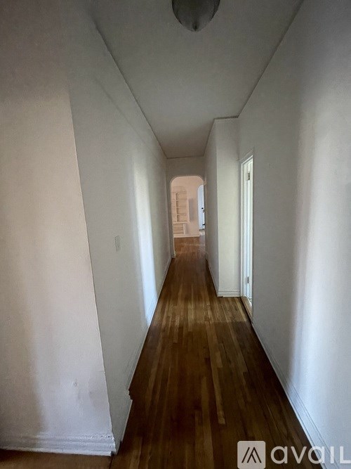 A long hallway with wood floors and white walls.