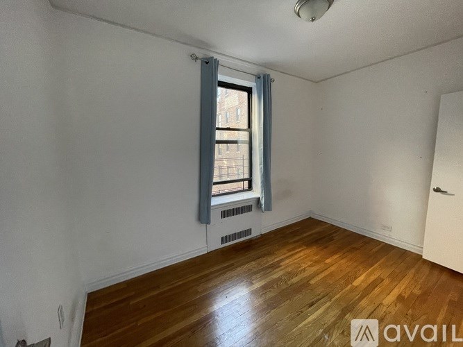 A room with wooden floors and a window with a view of a building outside.