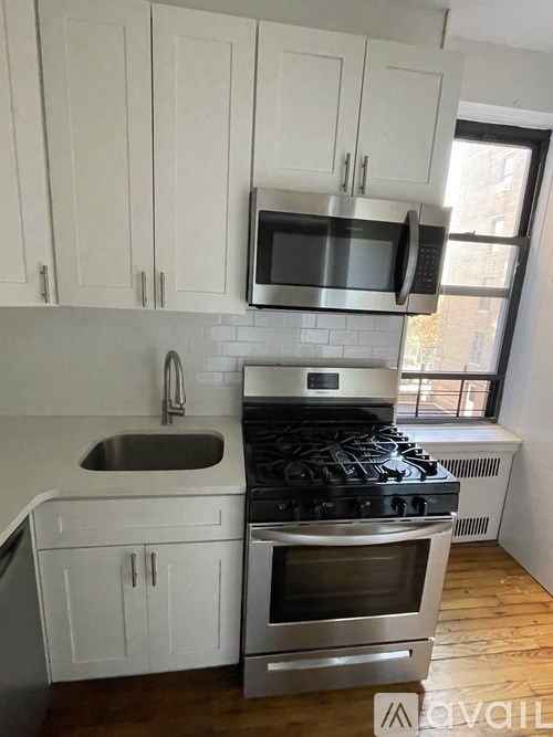 A kitchen with white cabinets and a stainless steel stove top.