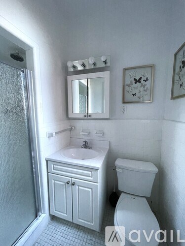 A white bathroom with a toilet, sink, and mirror.
