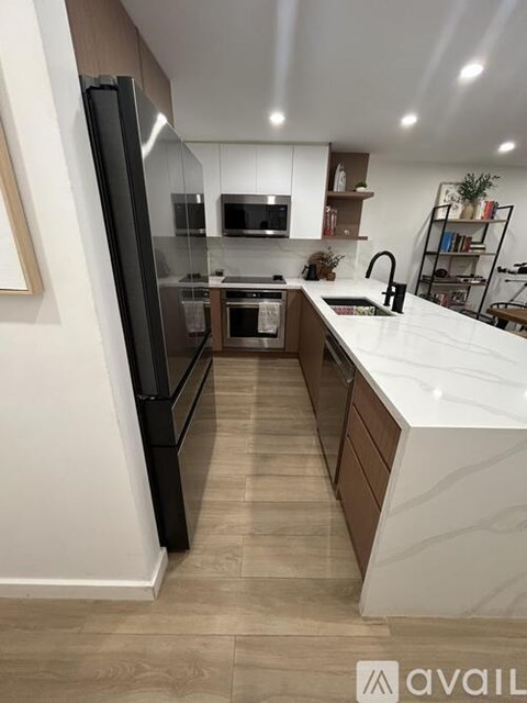 A modern kitchen with a black refrigerator and white countertops.