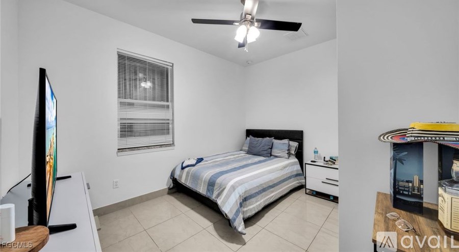 A bedroom with a bed, a ceiling fan, and a window with blinds.