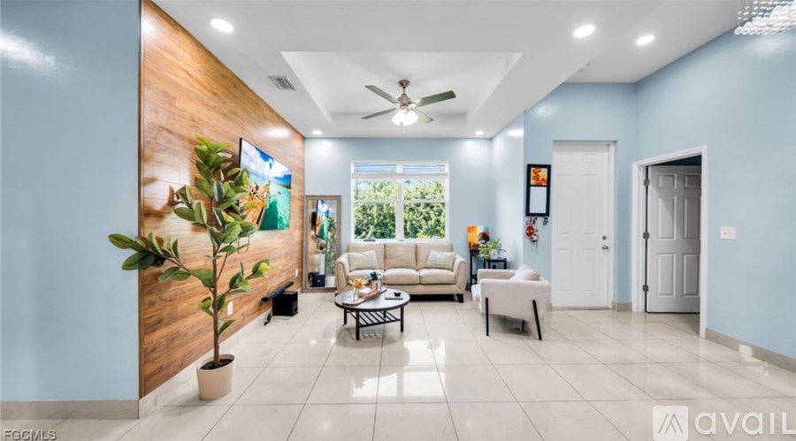 A living room with a large window, a ceiling fan, and a wooden accent wall.