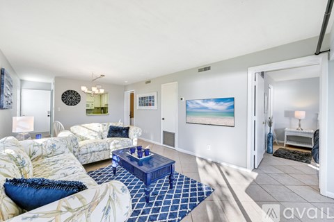 A living room with a blue coffee table and a painting on the wall.