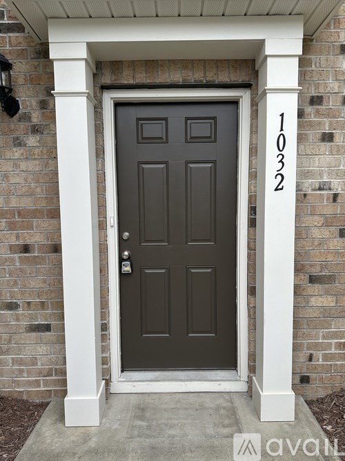 A grey door with a white frame and a number 1032 on the wall.