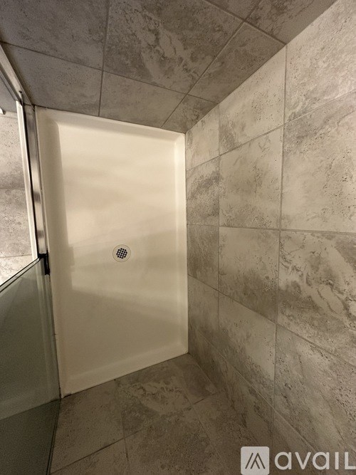 A white shower stall with a drain in the middle.