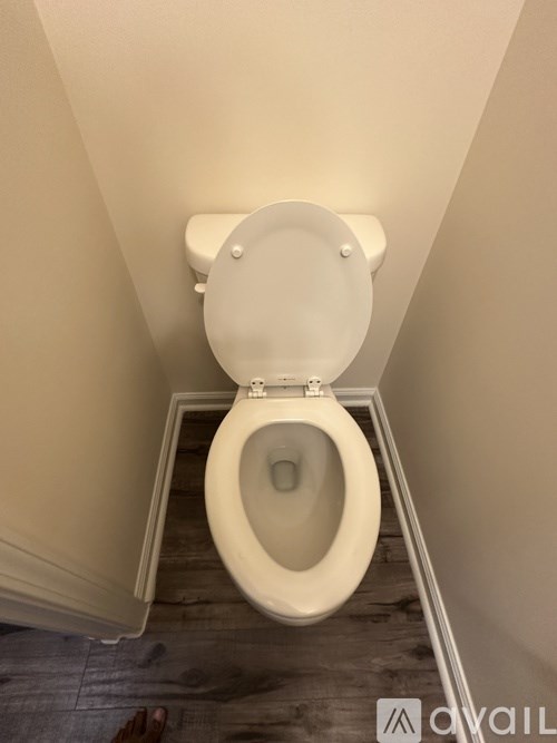 A toilet with a white lid is in a small bathroom.